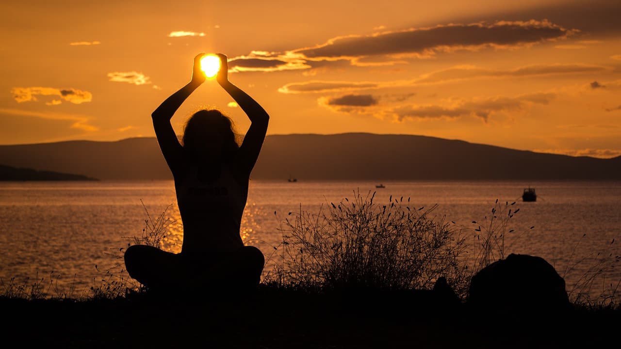 donna che pratica yoga al tramonto